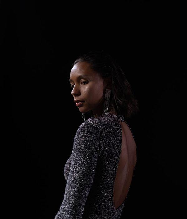 Woman holding a graceful yoga balance pose in a dark studio with red light.
